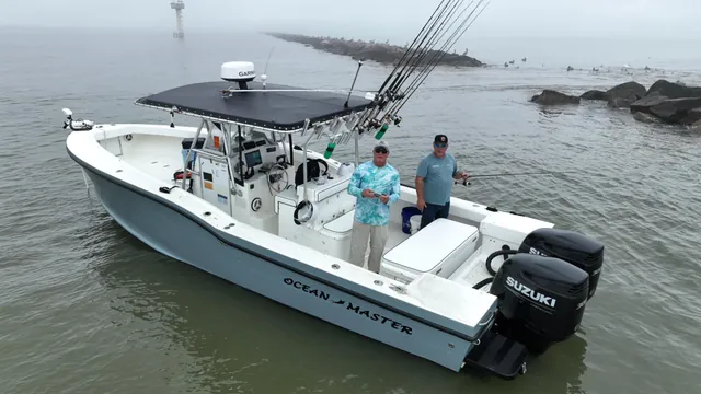 The 31 ft Ocean Master Half Time at the Galveston jetty, T-top with Garmin radar dome, twin outboards, two anglers on deck