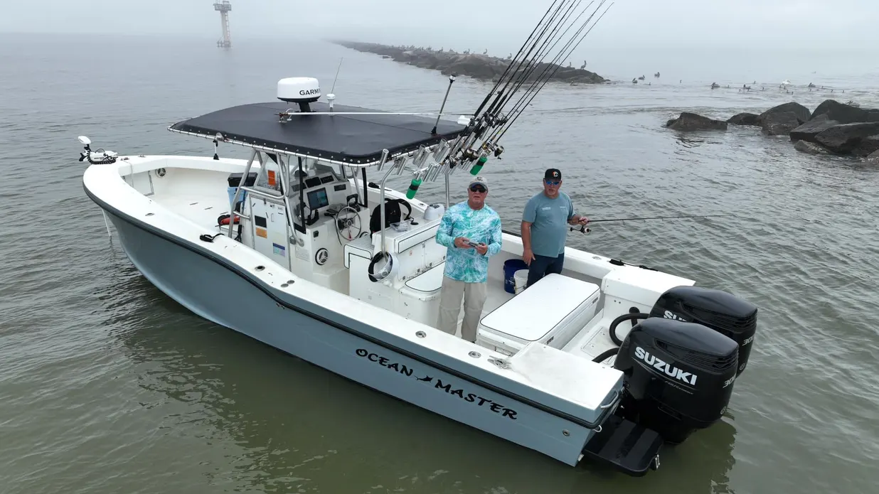 The 31 ft Ocean Master Half Time at the Galveston jetty in morning fog, two anglers on deck