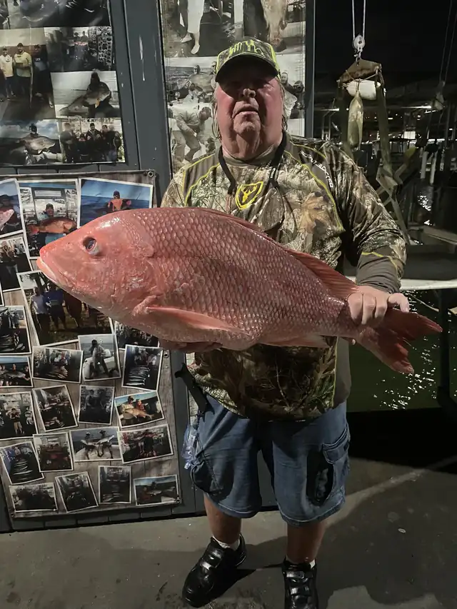 An angler holding a heavy red snapper at the cleaning station after a federal offshore trip out of Galveston