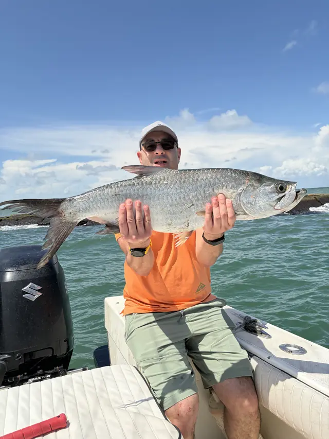 An angler holding a tarpon aboard the Half Time at the Galveston jetty
