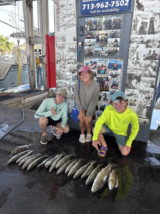 Three young anglers at the Galveston Offshore dock with a row of speckled trout from a jetty fishing trip