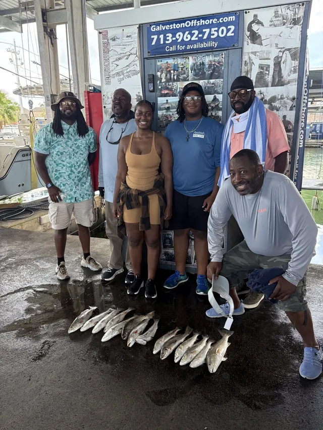 Family group at the Galveston Offshore dock with a row of speckled trout from a jetty fishing trip