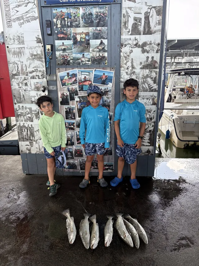 Three young anglers at the Galveston Offshore dock with their speckled trout catch from a jetty charter