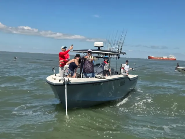 Bow-on shot of Half Time with anglers, Galveston bay water, freighter behind