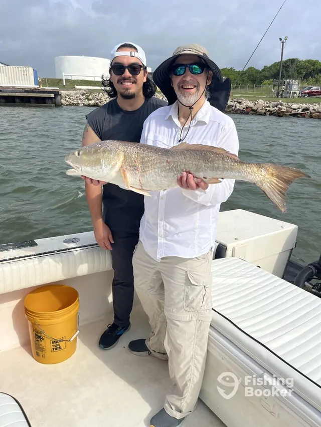 Two anglers proudly holding a large redfish aboard Half Time