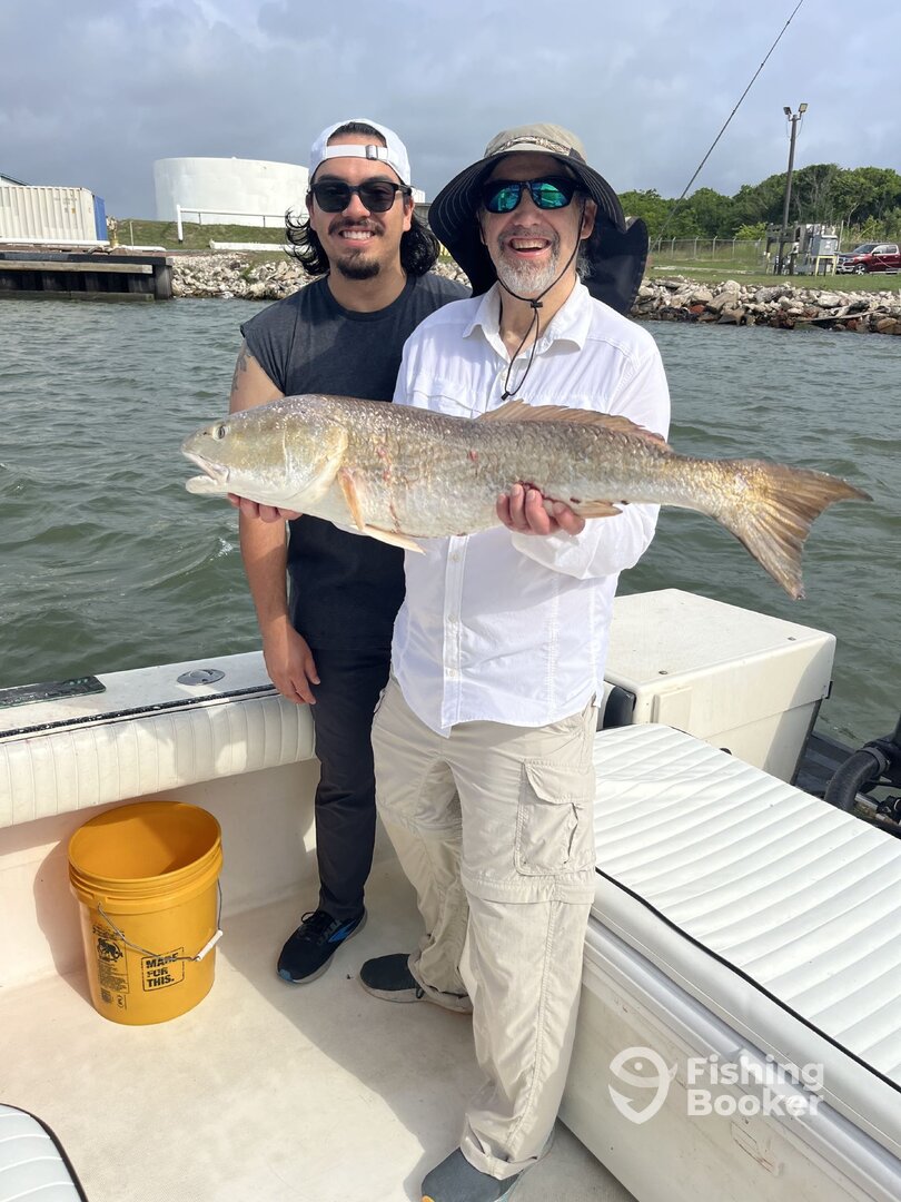 Two anglers proudly holding a large redfish aboard Half Time