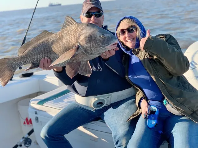 Two anglers with a large black drum caught on a Galveston trip