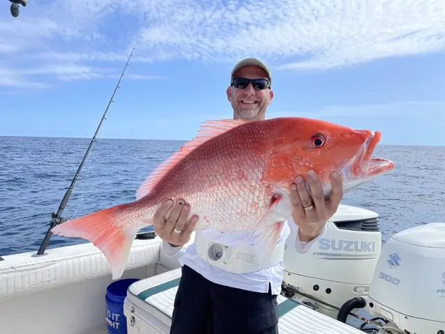 Angler holding a large red snapper caught offshore aboard Half Time