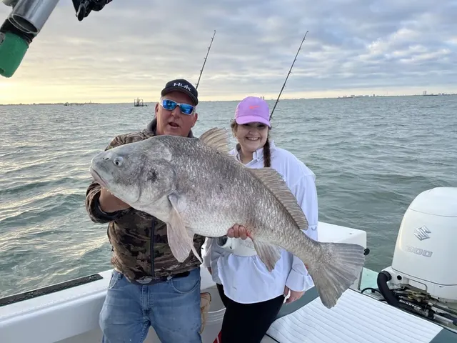 Father and son with a large black drum on a Galveston jetty trip
